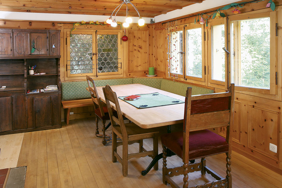 Die Stube des Waldfrieden Ferienhauses verfügt über einen grossen Holztisch und eine Eckbank.